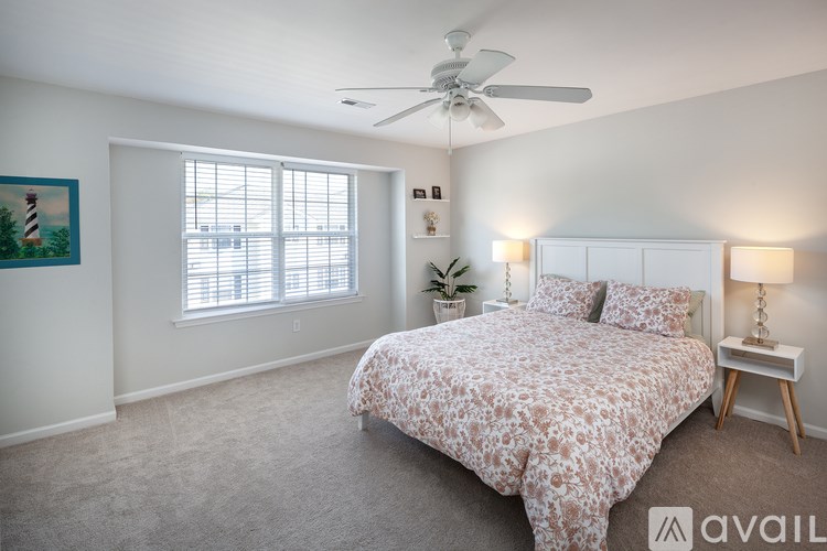 A bedroom with a bed, a ceiling fan, and a painting on the wall.