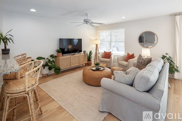 A living room with a grey couch, a television, and a ceiling fan.