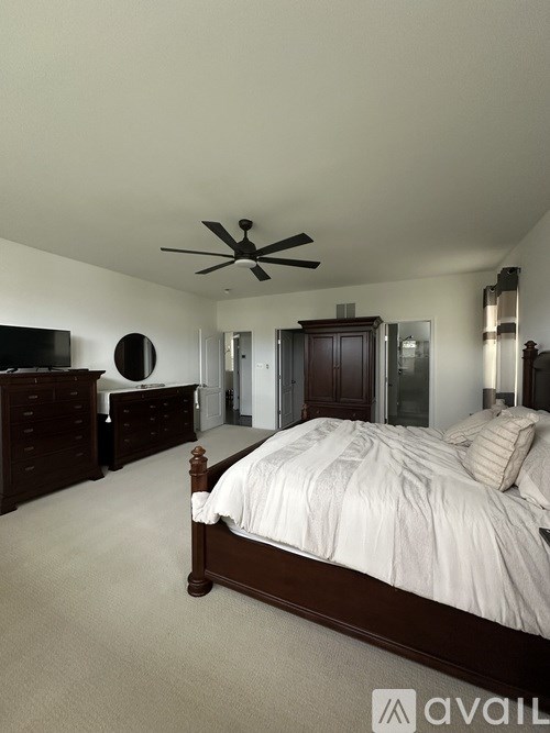 A bedroom with a large bed and a ceiling fan.