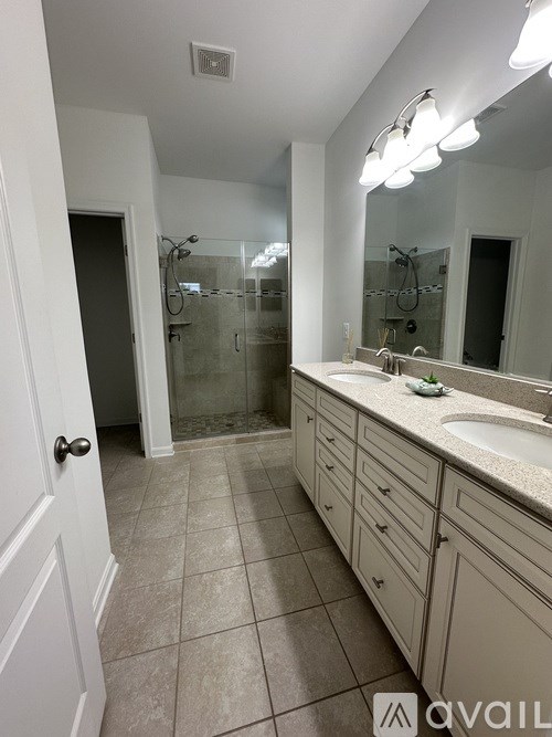A bathroom with a sink, mirror, and shower.
