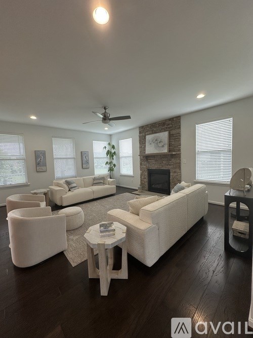 A living room with white furniture and a brick wall.