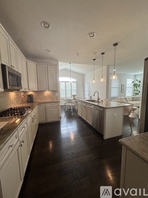 A kitchen with white cabinets and a dark floor.