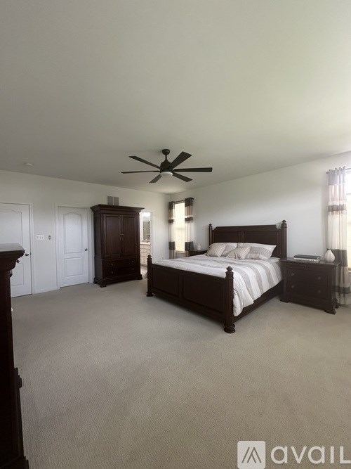 A bedroom with a large bed and a ceiling fan.
