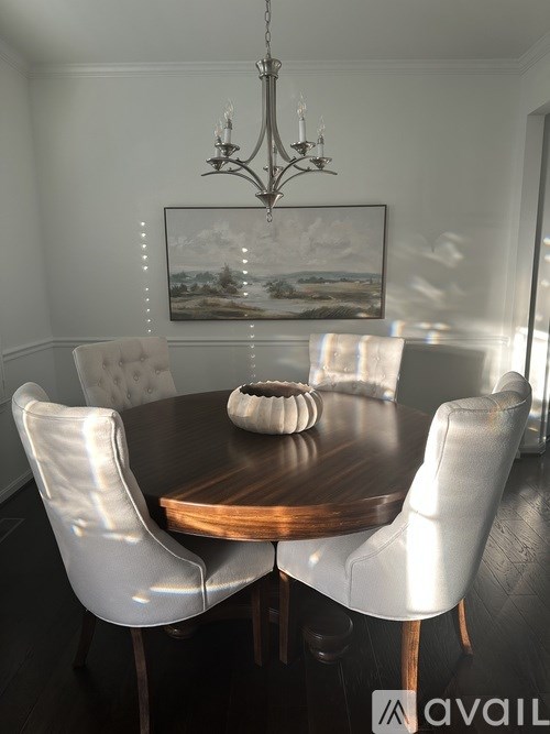 A dining room with a wooden table and white chairs.