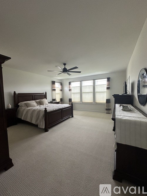 A bedroom with a large bed and a ceiling fan.