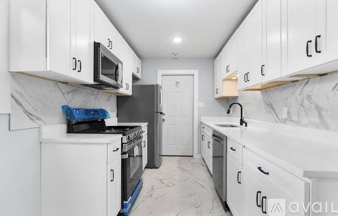 A kitchen with white cabinets and a marble floor.