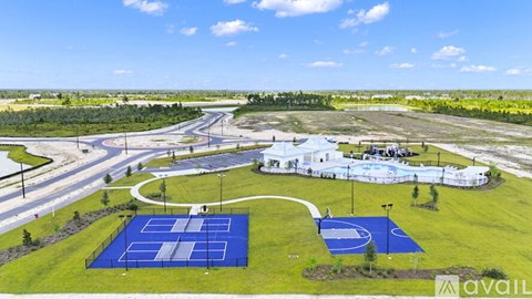 A tennis court is surrounded by a grassy area and a road.