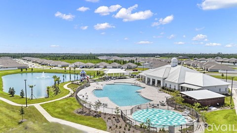 A large outdoor swimming pool surrounded by a grassy area and a building in the background.