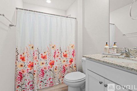A bathroom with a floral shower curtain and a toilet.