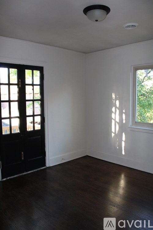 A room with a black door and a window with sunlight coming through.