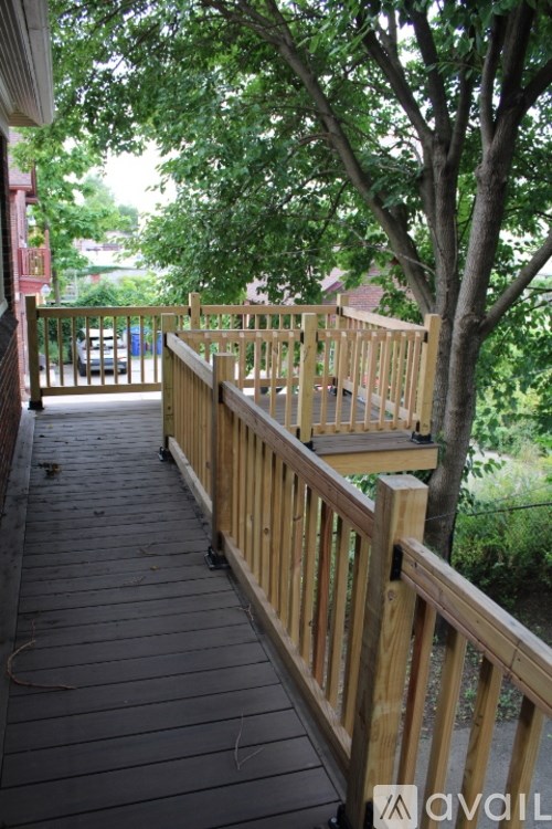 A wooden deck with a railing and trees in the background.