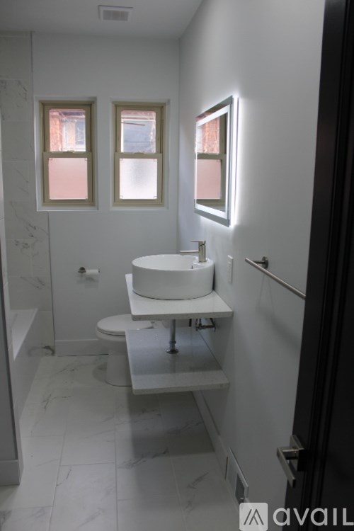 A bathroom with a toilet, sink, and mirror.