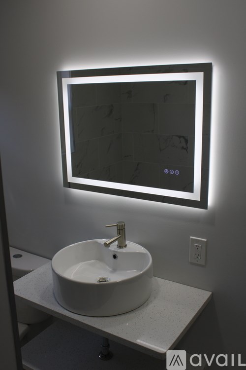 A bathroom sink under a mirror with lights around it.