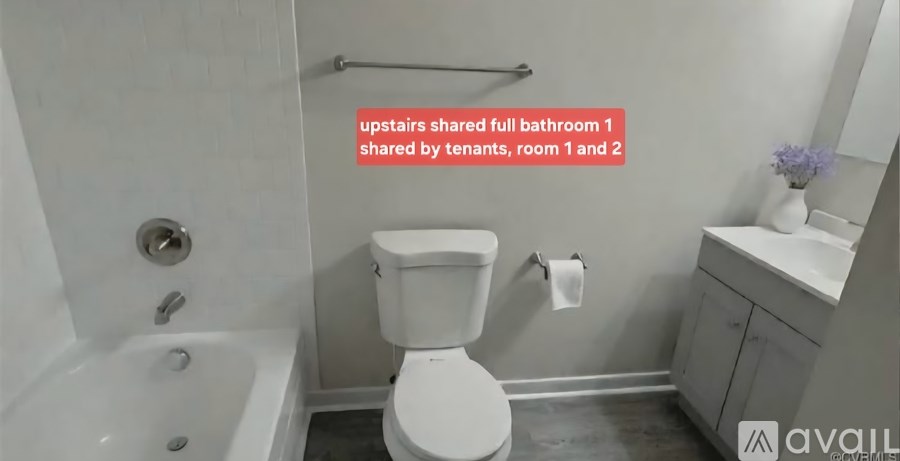 A white toilet in a bathroom with a tub and sink.
