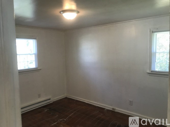 A room with a window and a wooden floor.