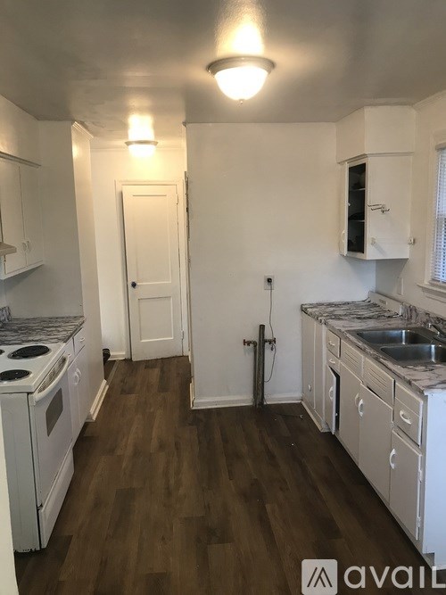 A kitchen with white appliances and wooden floors.