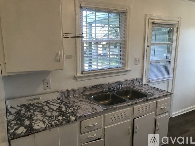 A kitchen with a marble countertop and white cabinets.
