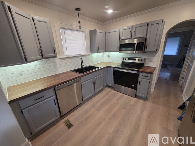 A kitchen with wooden floors and grey cabinets.
