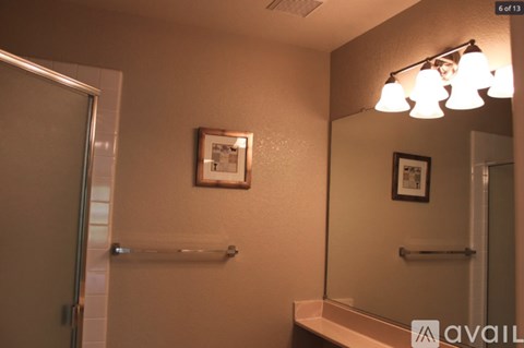 A bathroom with a mirror, a light, and a picture on the wall.