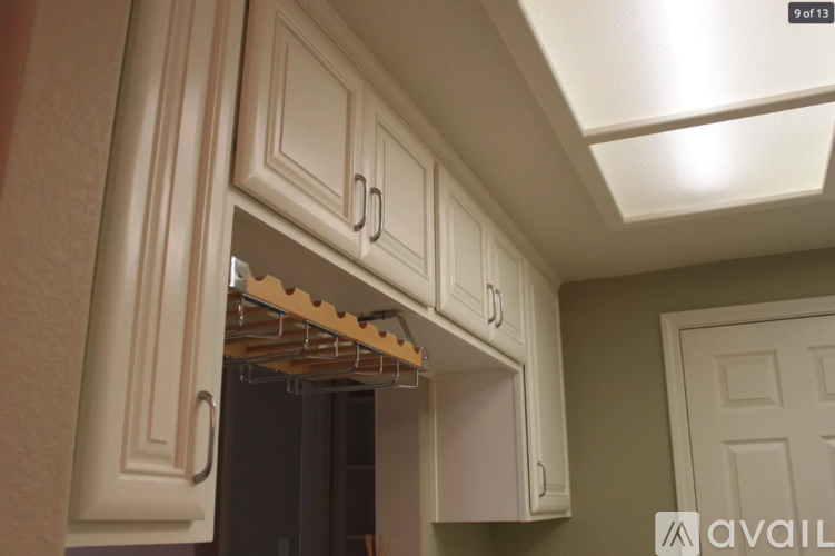 A kitchen with white cabinets and a shelf with clothes hanging on it.