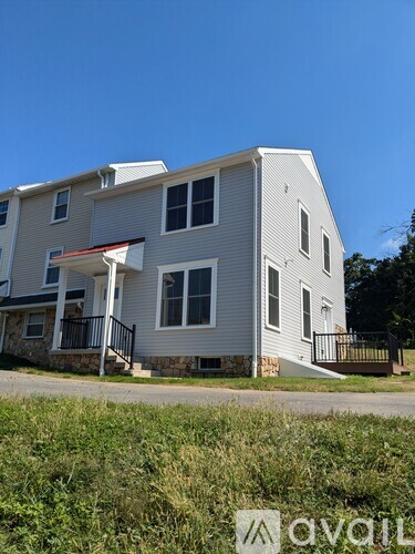 A man is painting the exterior of a two-story house.
