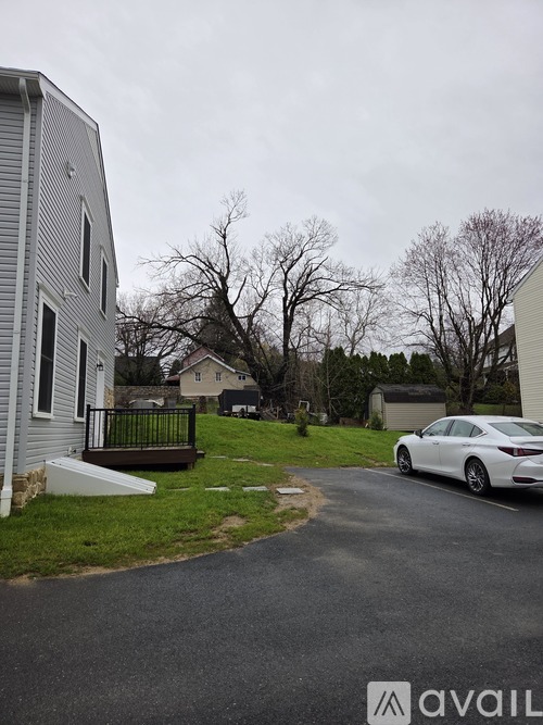 A man is standing in front of a grey house with orange cones around it.