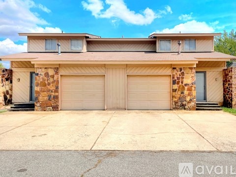 A house with a stone wall and two garages is available for rent.