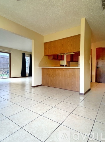 A kitchen with wooden cabinets and a white tile floor.
