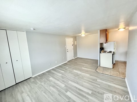 A kitchen area with a white fridge, cabinets, and a wooden floor.