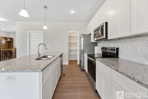 A kitchen with white cabinets and a marble countertop.