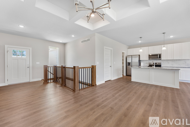 A spacious living room with a wooden floor and a staircase with a railing.