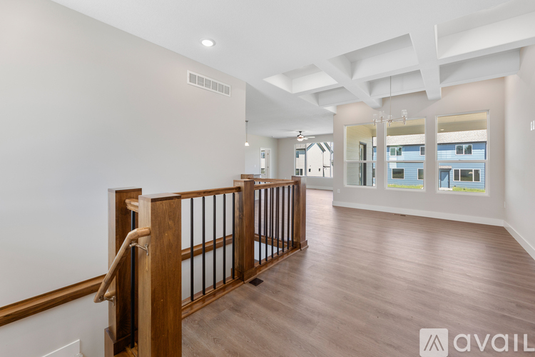 A spacious room with wooden flooring and a balcony with a railing.