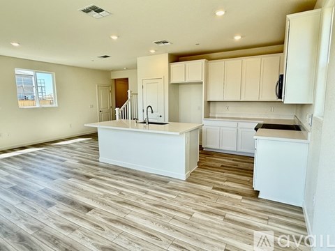 A kitchen with white cabinets and a wooden floor.