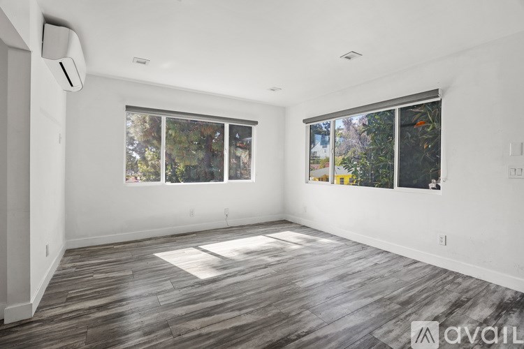 A spacious room with wood flooring and large windows.