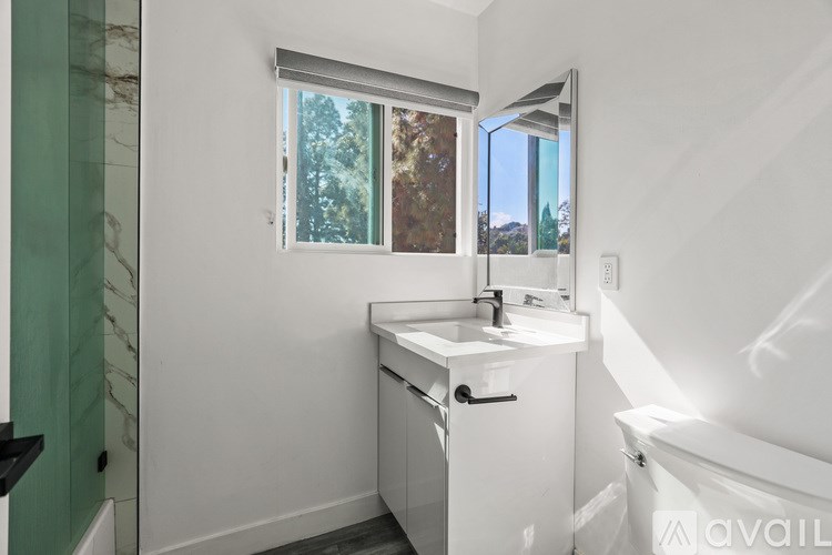 A white bathroom with a window and a sink.