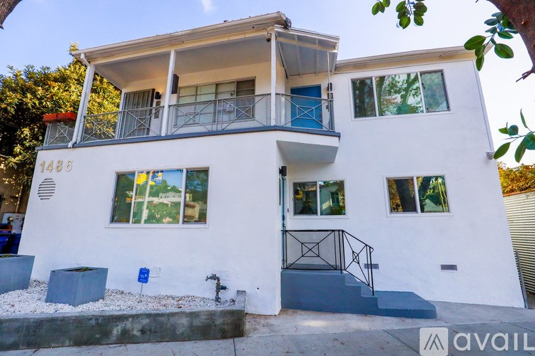 A white two-story house with a balcony on the second floor.