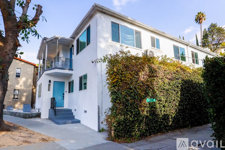 A white two-story house with a blue door and windows.