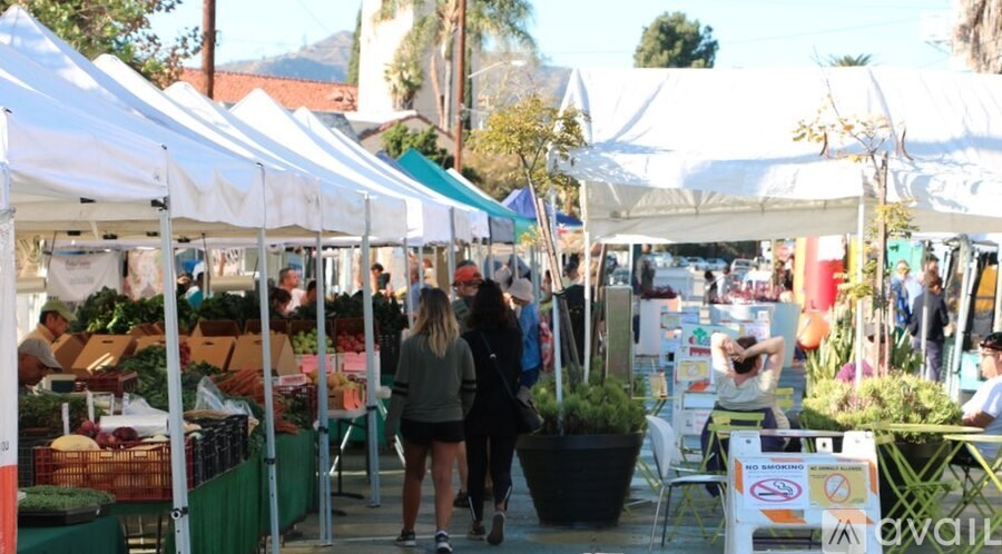 A market with white tents and people shopping.