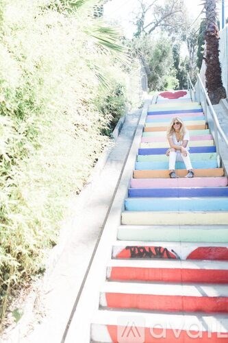 A woman is sitting on a multi-colored staircase.