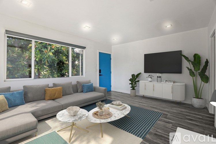 A living room with a grey sofa, a white coffee table, and a TV on the wall.