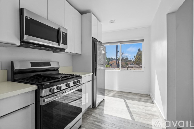 A modern kitchen with white cabinets and stainless steel appliances.