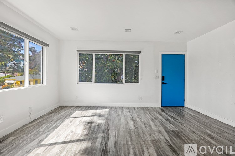 A room with a blue door and a window with a view of trees.