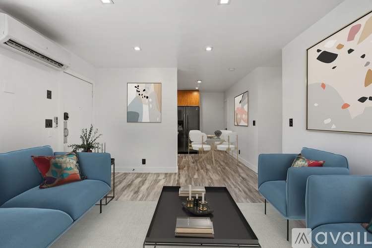 A living room with a blue couch and a painting on the wall.
