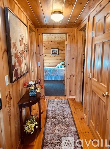 A hallway with wooden walls and a rug on the floor.