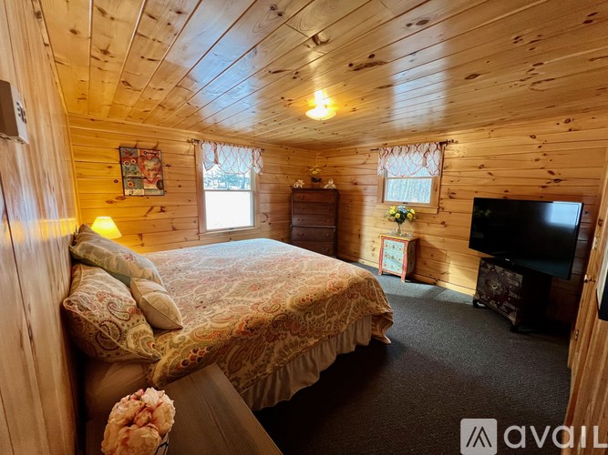A bedroom with a bed, a television, and a window with curtains.
