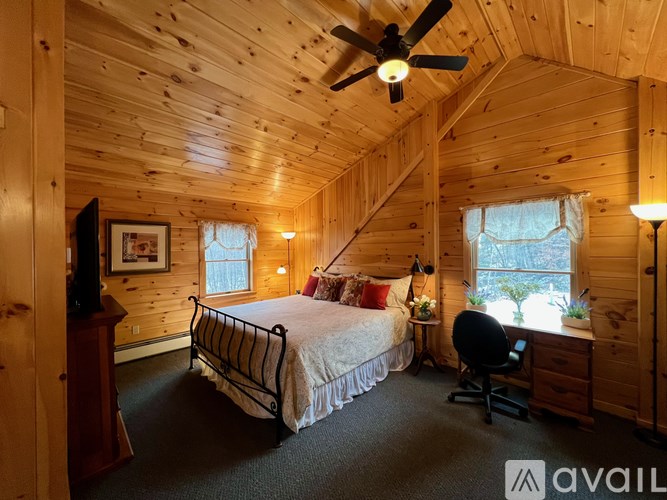 A bedroom with a bed, chair, and a ceiling fan.