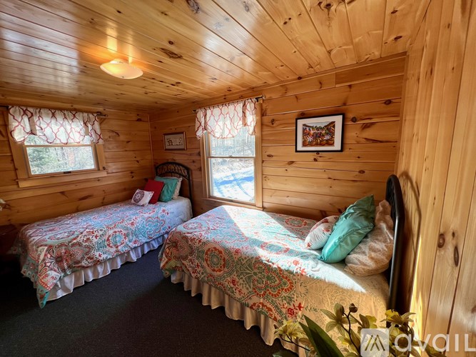 Two twin beds in a wooden cabin with floral bedspreads.