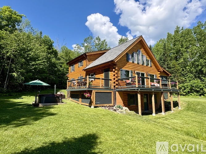 A wooden house with a deck and a hot tub in the yard.