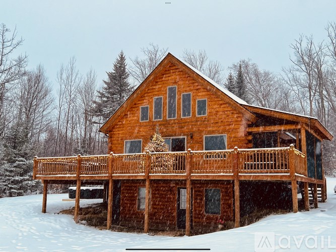 A wooden house with a balcony covered in snow.