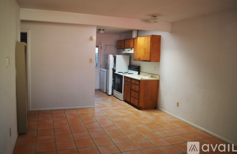A kitchen area with tile flooring and wooden cabinets.